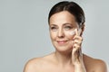 Middle aged woman applying anti-aging cream on her face