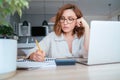 Beautiful middle-aged woman in glasses making marks in financial documents at home office. Small business, home finances, money Royalty Free Stock Photo