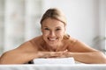 Beautiful middle aged woman lying on table in spa salon, waiting massage Royalty Free Stock Photo