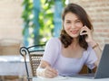 The beautiful middle-aged woman sitting in food shop and working with a laptop notebook computer and talking on the phone. Work Royalty Free Stock Photo