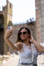 beautiful middle aged woman takes a selfie outdoors on a lakeside terrace