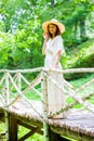 Beautiful middle-aged woman in a white summer dress and hat stands on a birch bridge. fashion and style Royalty Free Stock Photo