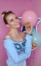 Beautiful middle aged women tasting colorful donut. Soft colors. Studio portrait over pink background