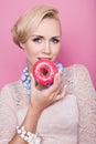 Beautiful middle aged women tasting colorful donut. Soft colors