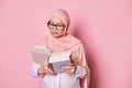 Beautiful Middle Eastern Muslim Woman In Pink Hijab, Reading Book Isolated On Color Background. Educated People Concept