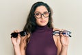 Beautiful middle eastern woman holding different glasses clueless and confused expression