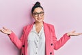 Beautiful middle eastern woman wearing business jacket and glasses smiling showing both hands open palms, presenting and Royalty Free Stock Photo