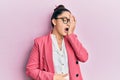 Beautiful middle eastern woman wearing business jacket and glasses yawning tired covering half face, eye and mouth with hand