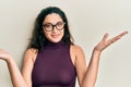 Beautiful middle eastern woman wearing casual clothes and glasses clueless and confused with open arms, no idea and doubtful face