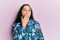 Beautiful middle eastern woman wearing casual floral jacket bored yawning tired covering mouth with hand