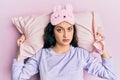 Beautiful middle eastern woman wearing sleep mask and pajama sleeping on pillow clueless and confused expression