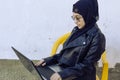 Beautiful middle-eastern working with the laptop. Cute Arabian Muslim woman in hijab posing with laptop outdoors. Blogger, vlogger