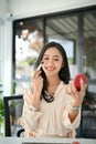 Beautiful millennial Asian female office worker putting on her makeup in her office Royalty Free Stock Photo