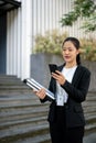 A beautiful Asian businesswoman is texting someone while standing outside of the building Royalty Free Stock Photo