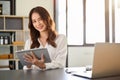 Beautiful millennial Asian businesswoman using her digital tablet at her desk Royalty Free Stock Photo