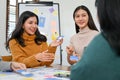 Beautiful Asian female UI designer discussing and presenting her new prototype with her team Royalty Free Stock Photo