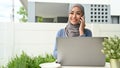 Beautiful millennial Asian Muslim woman in the backyard and talking on the phone Royalty Free Stock Photo