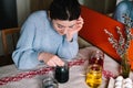 Beautiful millennial girl dyeing Easter eggs in jars at table Royalty Free Stock Photo