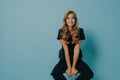 Beautiful young smiling lady hair in black casual t-shirt and jeans sitting on chair in studio Royalty Free Stock Photo