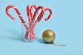 Beautiful minimalist simple composition with Christmas lollipops in a transparent glass and golden Christmas ball, Christmas tree Royalty Free Stock Photo