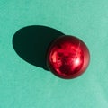 Beautiful minimalistic Christmas background. One small glass Christmas tree red ball on a light green background Royalty Free Stock Photo