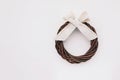 Beautiful minimalistic Christmas wreath made of willow branches with cotton ribbon on white wooden background.