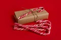 Beautiful minimalistic composition of Christmas items, gift box wrapped in kraft wrapping gift paper with tied bow and sweet candy Royalty Free Stock Photo