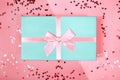 Beautiful mint gift box with atlas ribbon on coral background with sparkling stars, festive concept