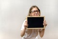 Beautiful mischievous girl with glasses holding a sign in her hands. copy-space