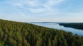 A beautiful mixed forest along the shore of the huge calm lake. Blue sky. Royalty Free Stock Photo