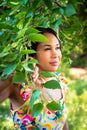 A beautiful mixed race African American woman in yellow floral dress standing in the forest on a sunny summer day parts a tree