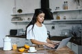 Beautiful mixed race girl in white robe using laptop in morning