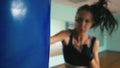Beautiful Mixed Race Kickboxing woman training punching bag in fitness studio fierce strength fit body kickboxer series
