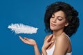 Beautiful mixed race woman catching white ostrich feather falling on her palm