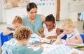 Beautiful mixed race woman crouching down to watch a group of diverse children colour in preschool. Small and cute kids Royalty Free Stock Photo