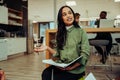 Beautiful mixed race woman explaining ideas to colleagues sitting with note book and ben in office lounge before Royalty Free Stock Photo