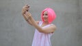 Beautiful mixed race woman in pink wig taking selfie using phone smiling and spinning enjoying life