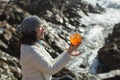 Beautiful mixed -race woman sitting with a cocktail on the background of sea rocks on sunny day. Royalty Free Stock Photo