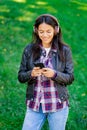 Beautiful mixed race young woman listening to music on headphones with smartphone. Hispanic hipster girl dancing to Royalty Free Stock Photo