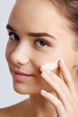 Beautiful model applying cosmetic cream treatment on her face. Close-up young beautiful face of girl applying moisturize cream. Royalty Free Stock Photo