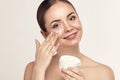 Beautiful model applying cosmetic cream treatment on her face on white background. Royalty Free Stock Photo