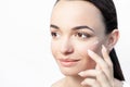 Beautiful model applying cosmetic drops of cream on her face on white background close-up Royalty Free Stock Photo