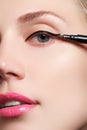 Beautiful model applying eyeliner close-up on eye. Make-up Royalty Free Stock Photo
