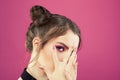 Beautiful model girl with fashion makeup hiding behind hands with manicured nails on bright pink background