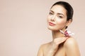 Beautiful Model Girl holding Orchid Flower on Shoulder. Beauty Woman with Perfect Healthy Skin and Natural Makeup. Body and Face Royalty Free Stock Photo