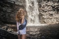 Beautiful model girl with long legs posing near a waterfall wearing jeans jacket. Royalty Free Stock Photo