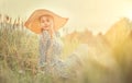 Beautiful model girl posing on a field, enjoying nature outdoors in wide brimmed straw hat Royalty Free Stock Photo