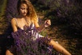 Beautiful model holding a bouquet of fresh lavenders relaxing in the spring or summer lavender field under the rays of the sun. Royalty Free Stock Photo