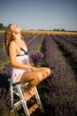 Beautiful model holding a bouquet of fresh lavenders relaxing in the spring or summer lavender field under the rays of the sun. Royalty Free Stock Photo