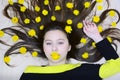 A beautiful model lies with dandelion flowers in her hair and a flower in her mouth. Top view Royalty Free Stock Photo